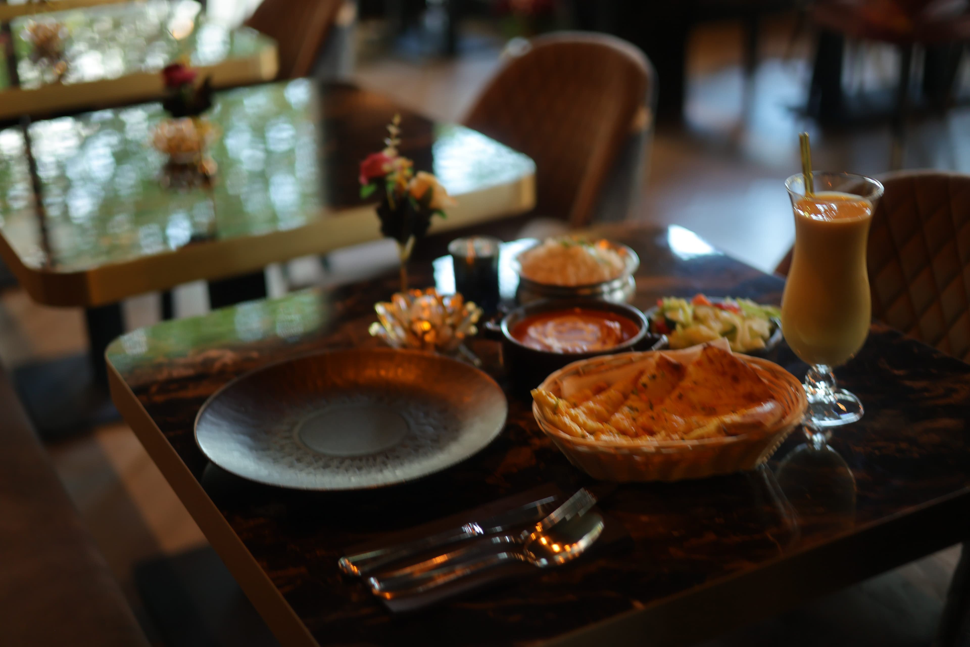 Curry geserveerd in een koperen pan met bijgerechten en kruiden bij The Tandoor Company Amsterdam